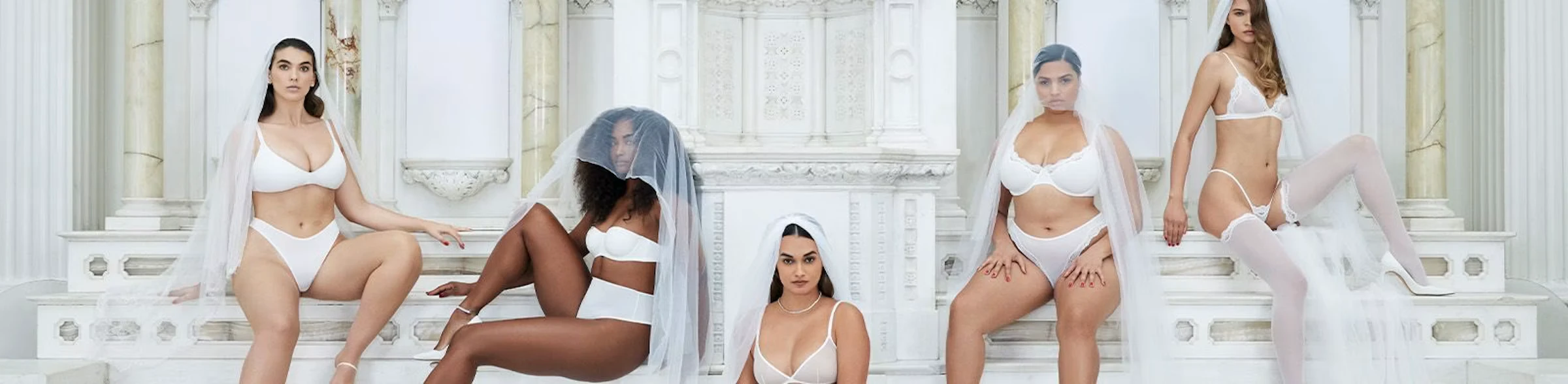 A wide shot of brides in white sets among marble columns