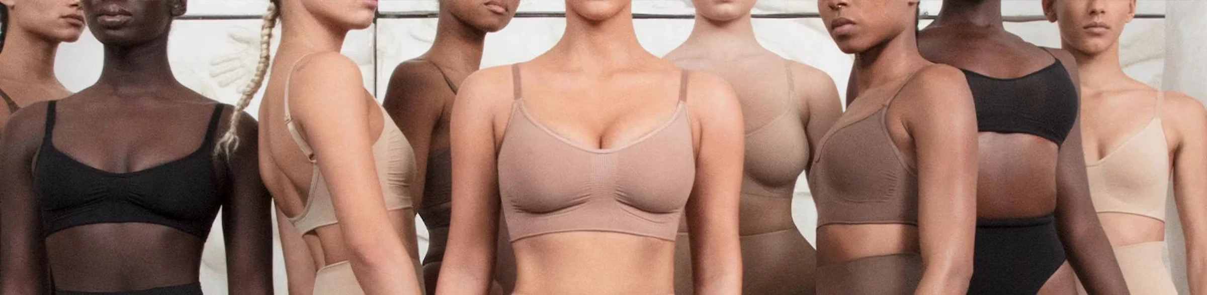 A row of models in black and nude bras and bodysuits