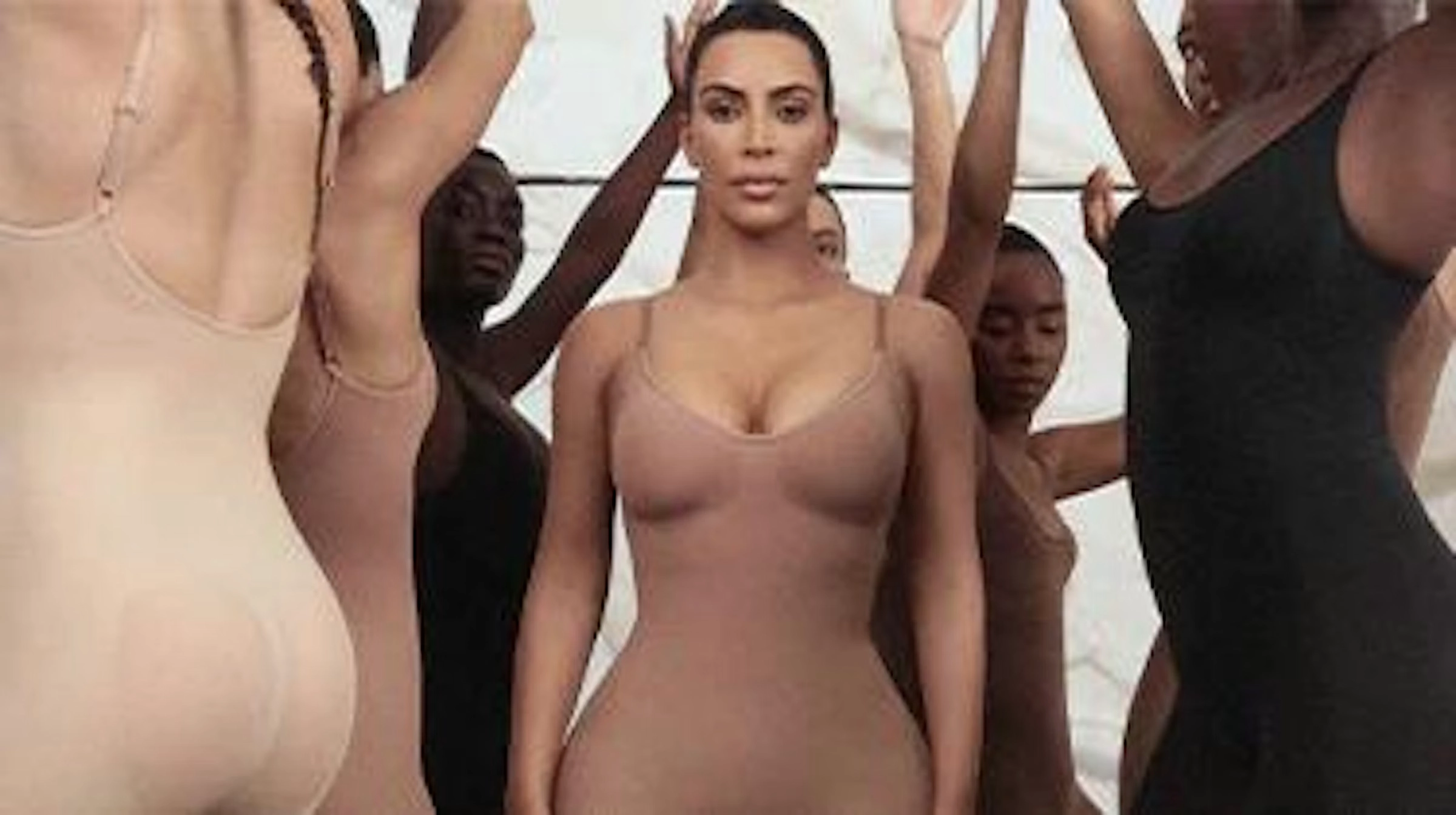 Models in brown, black and white bodysuits and knits stand in a line